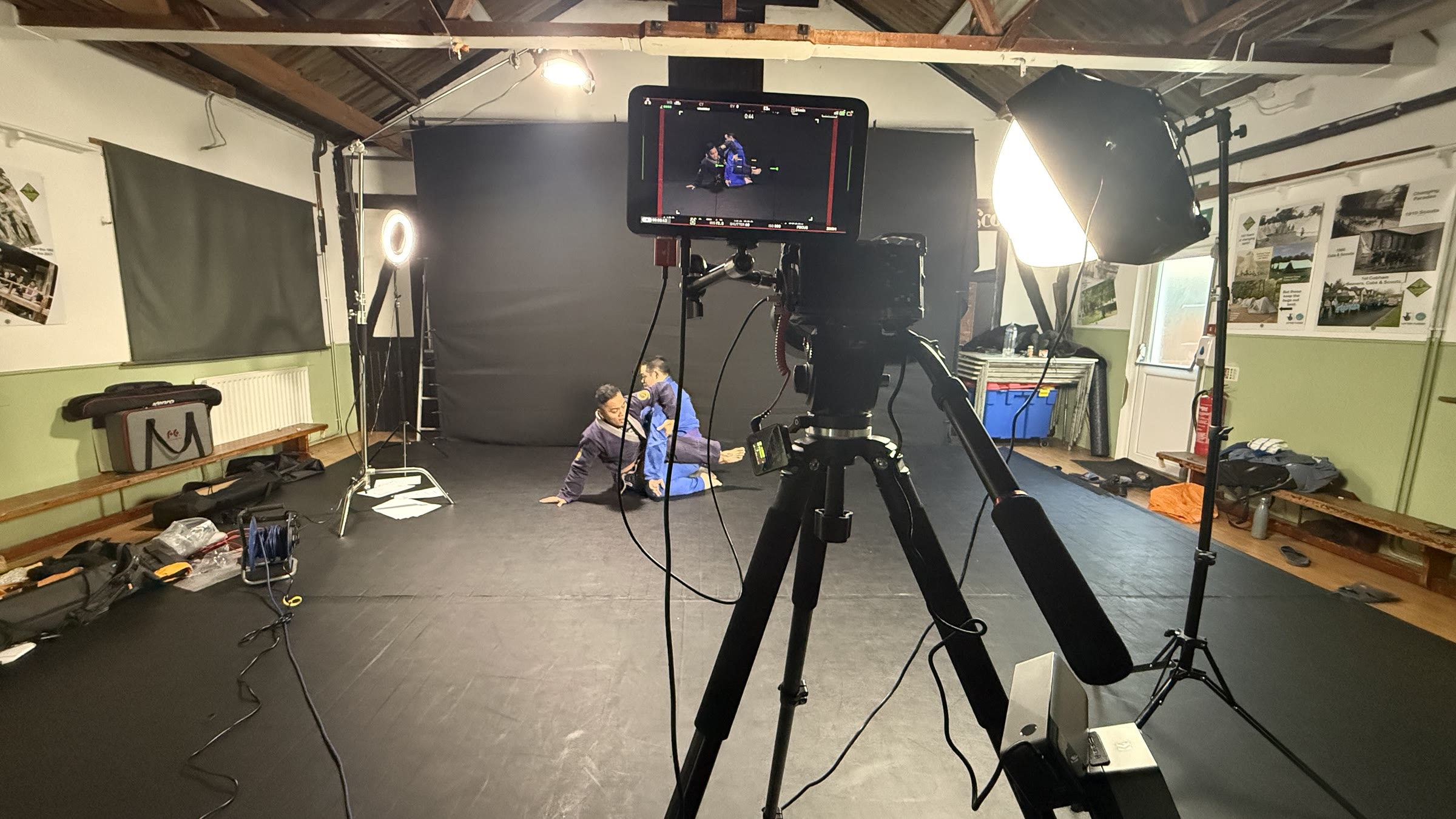 Full studio lighting and camera setup filming members on the mats