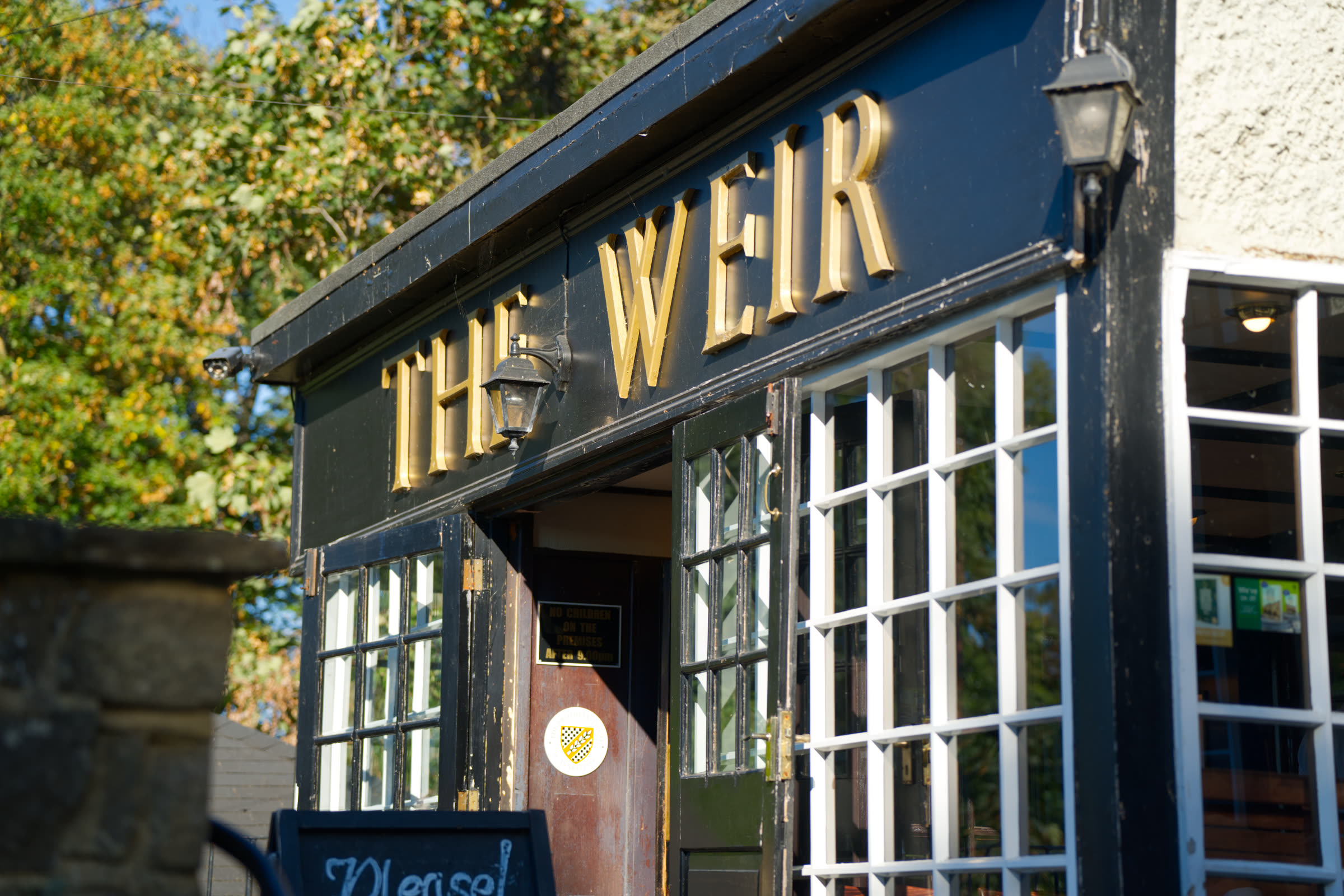 Gold lettered 'The Weir' signage above the pub entrance