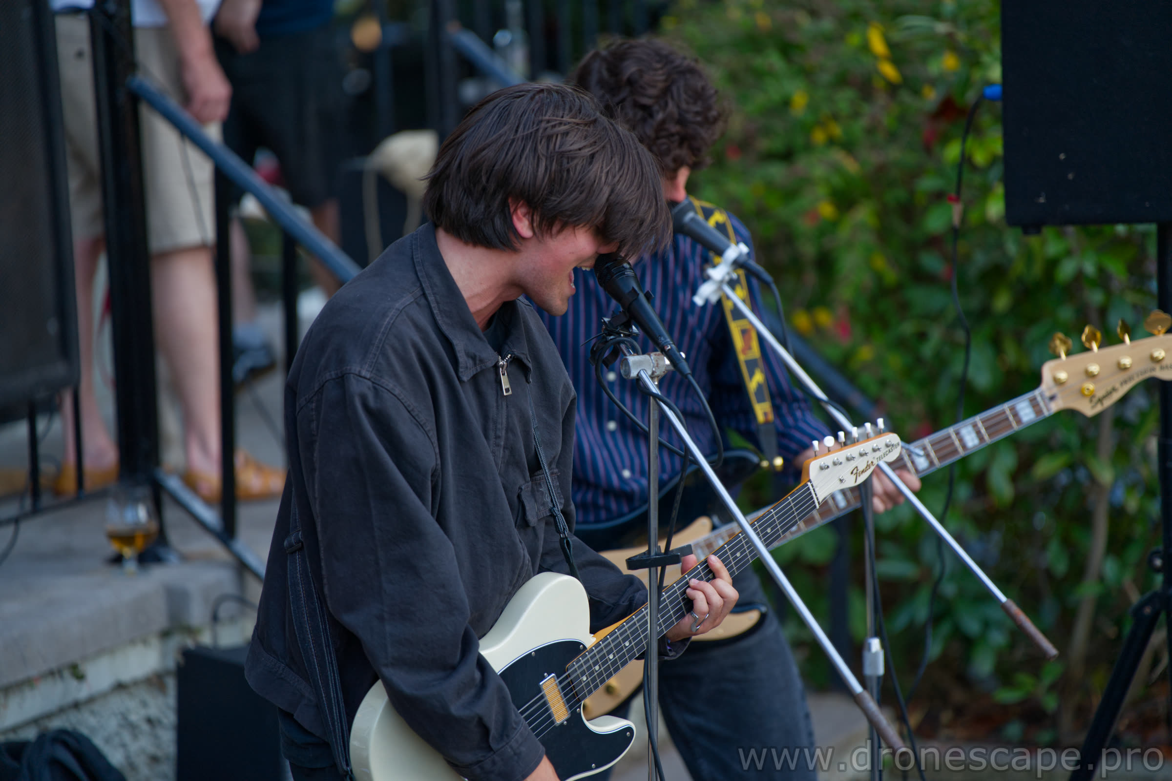 Two guitarists sharing a microphone on stage