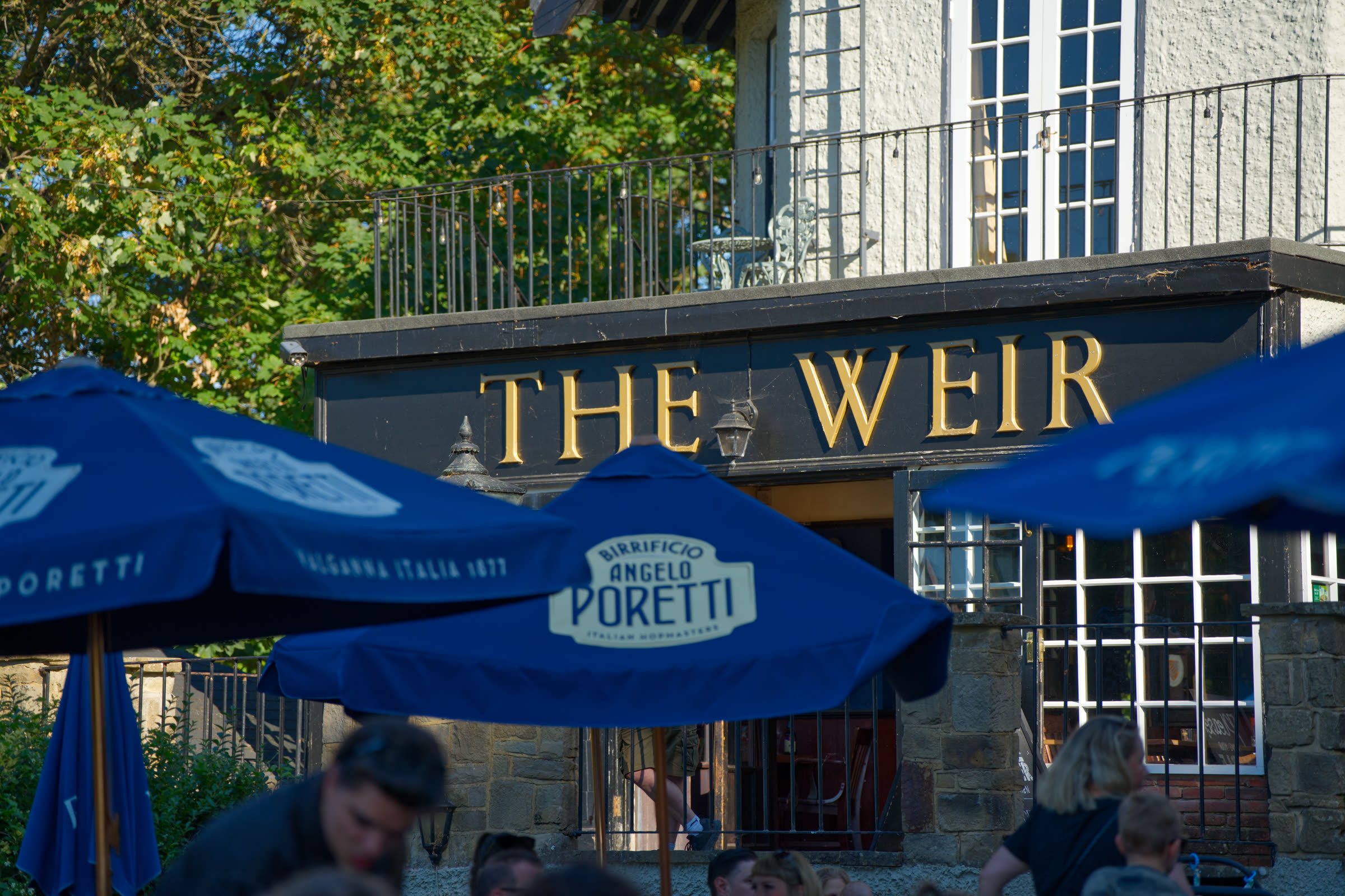 Timbered frontage and gold signage seen over the garden parasols
