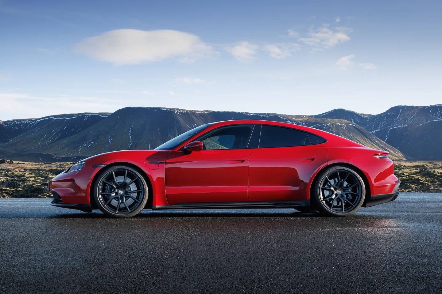 Red Porsche Taycan photographed side-on against a mountain landscape